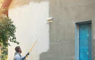 House painter painting building exterior with roller- is it better to spray or roll exterior paint